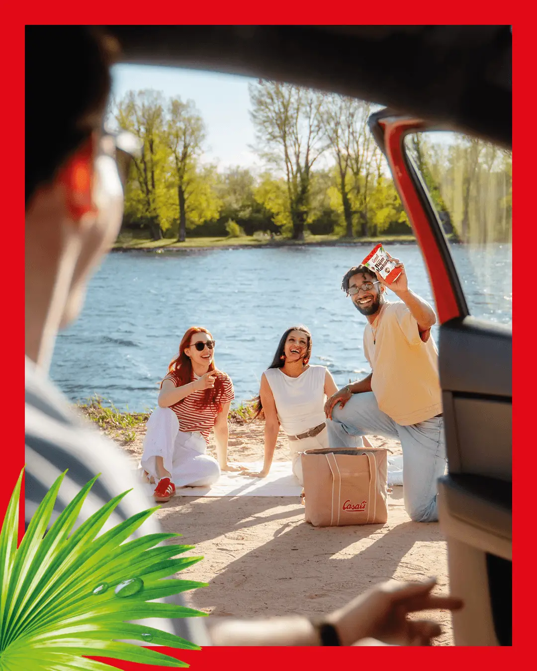 Junge Menschen Picknicken am See mit einer Packung Rum-Kokos