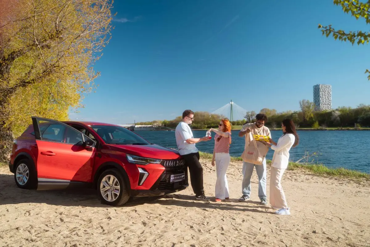 Junge Leute stehen an See mit rotem Auto