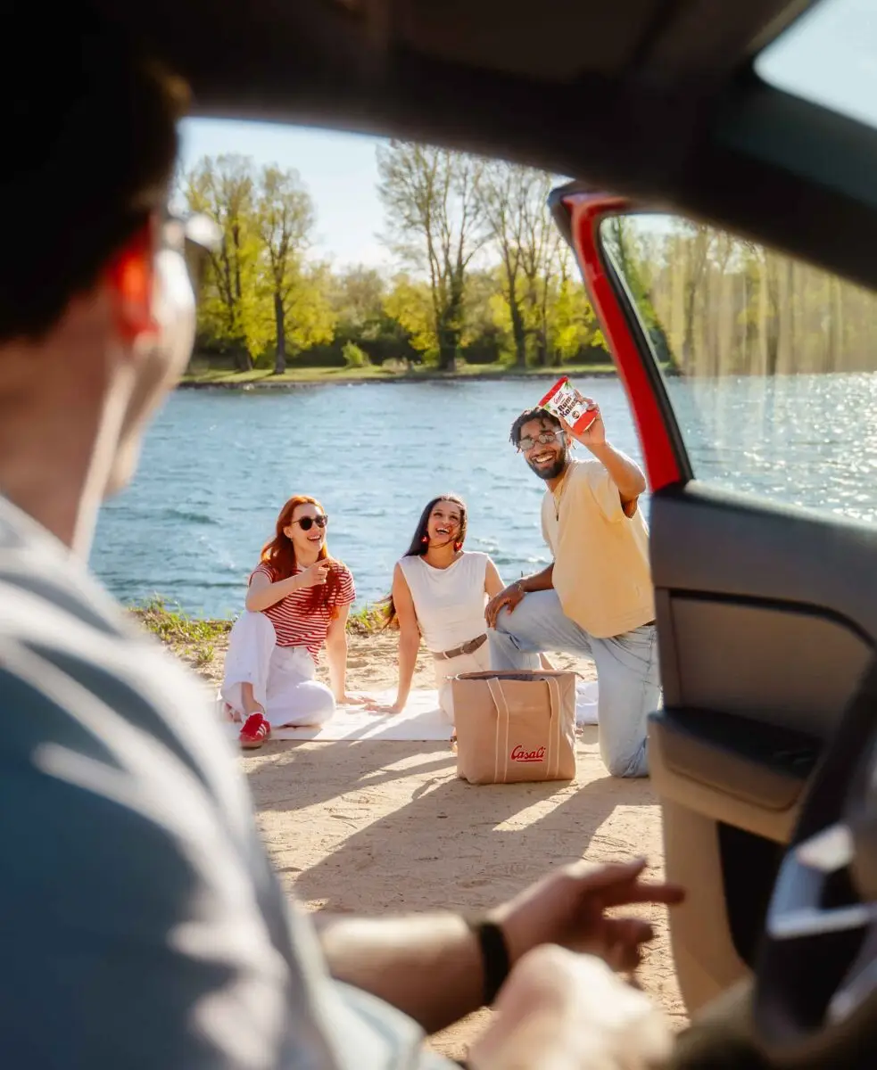 Junge Menschen Picknicken am See mit einer Packung Rum-Kokos