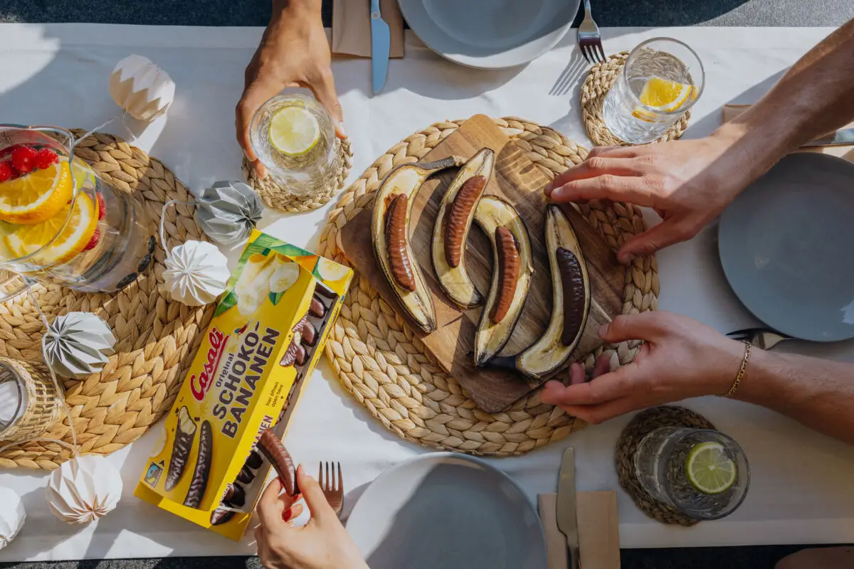 Eine Packung Schoko-Bananen auf gedecktem Tisch mit Bananenhälften mit Schoko-Bananen