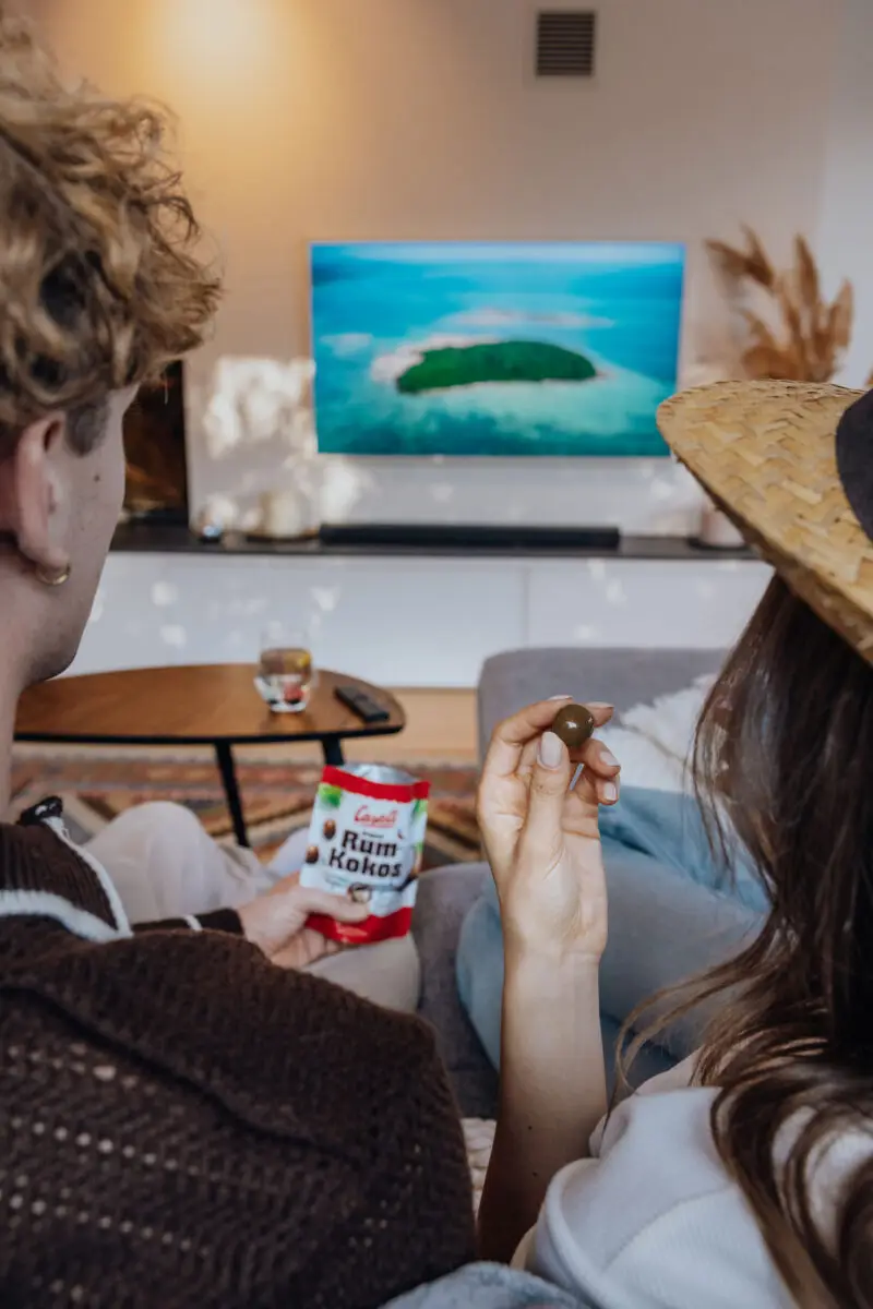 Junge Menschen teilen sich eine Packung Casali Rum-Kokos Kugeln beim fernsehen