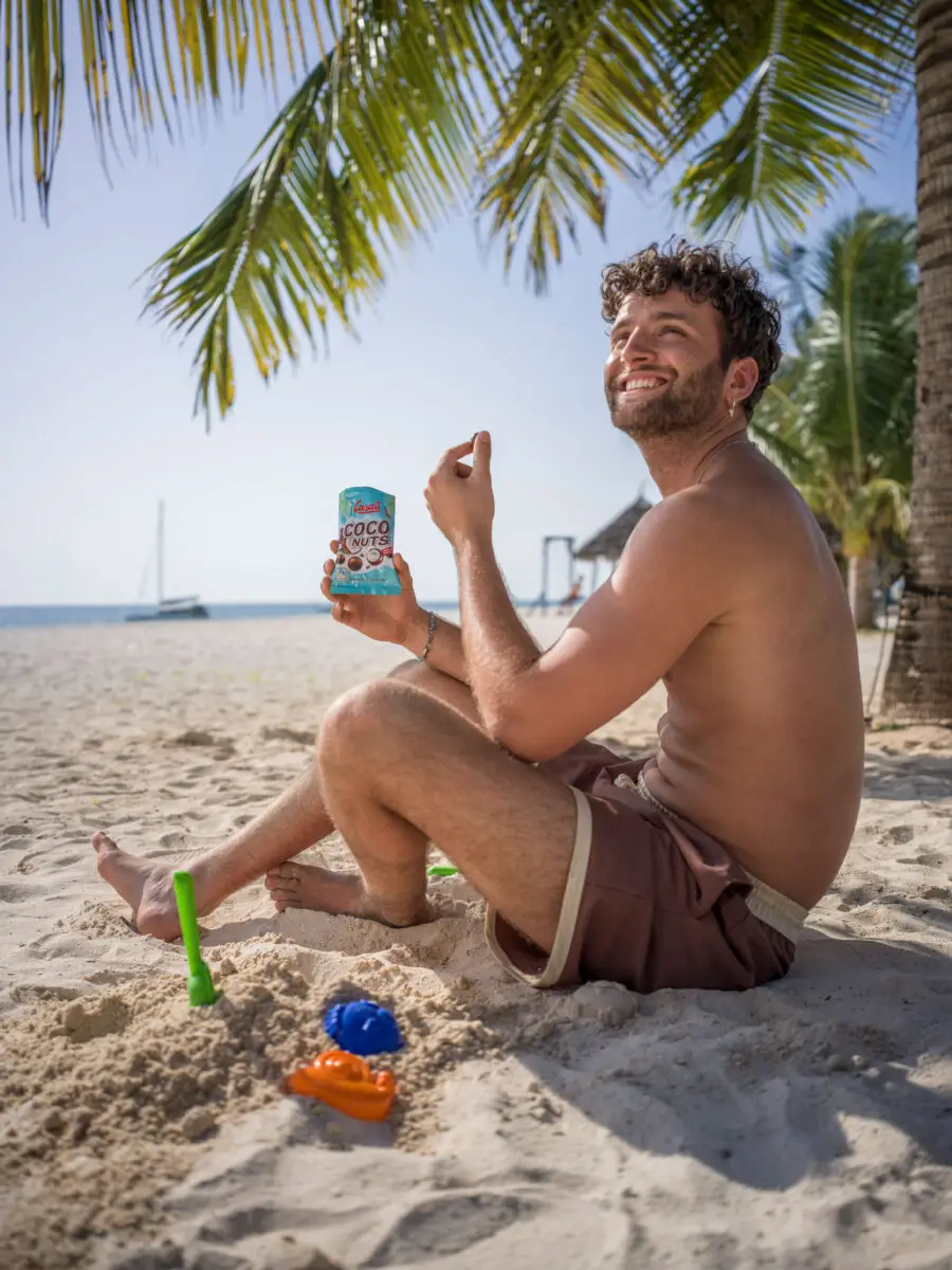 Ein Mann isst eine Packung Casali Coconuts am Strand