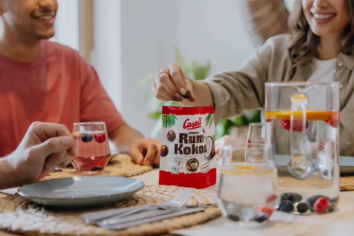 Junge Menschen teilen sich eine Packung Casali Rum-Kokos Kugeln am Tisch
