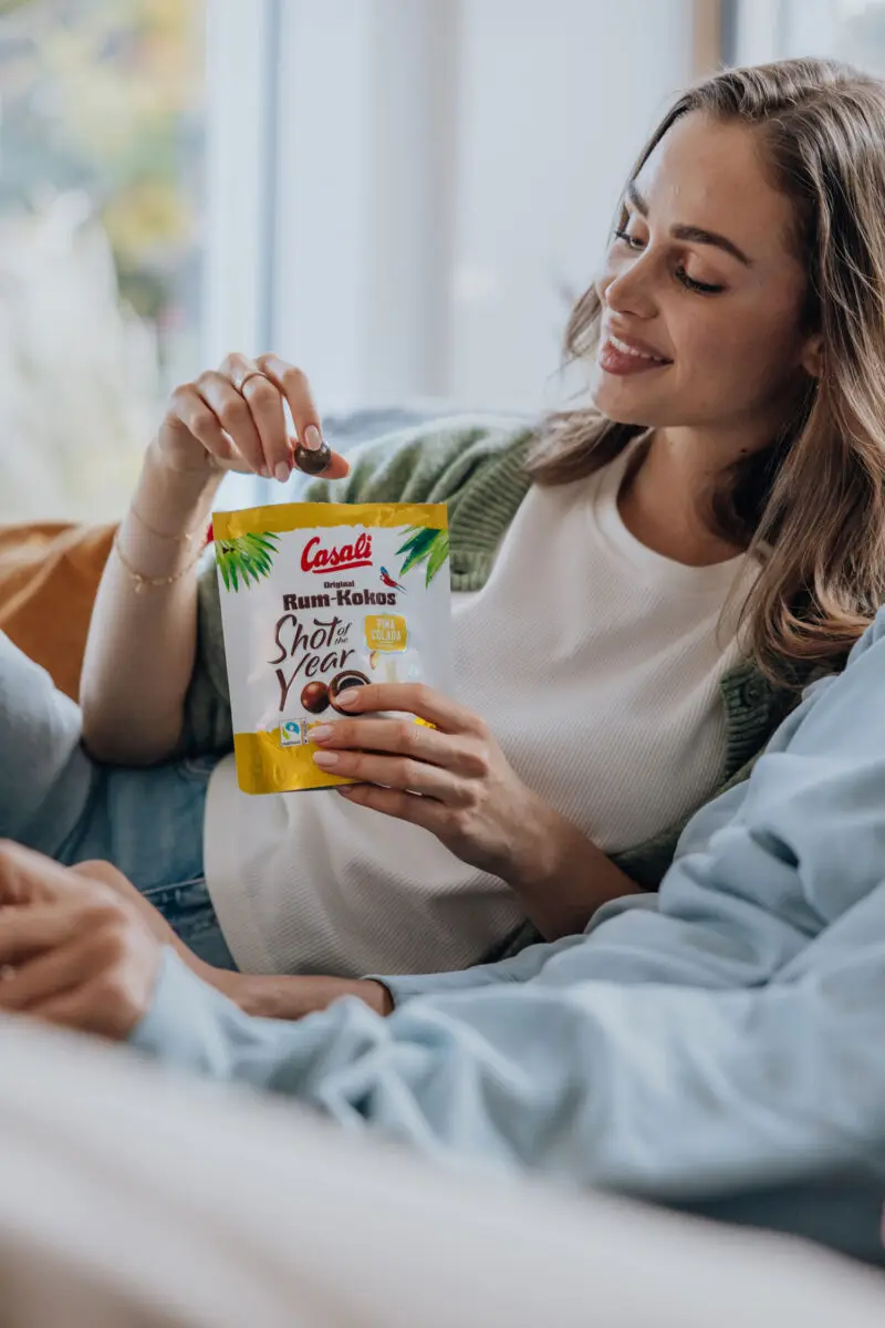Eine junge Frau isst eine Packung Rum-Kokos Shot of the year